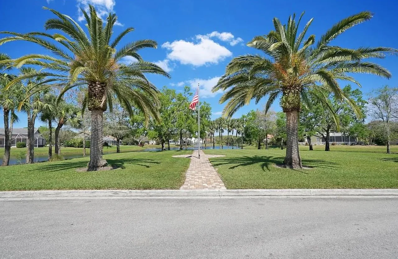 Palm trees, a brick walkway, and the lake at Westview Village